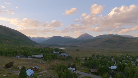 Aerial-push-over-houses-in-Crested-Butte,-Colorado-and-towards-mountain-landscape-on-the-horizon-on-a-beautiful-summer-day