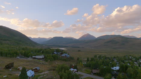 empuje aéreo sobre casas en crested butte, colorado y hacia el paisaje montañoso en el horizonte en un hermoso día de verano