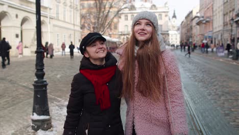 two friends walk together on a snowy street in a city