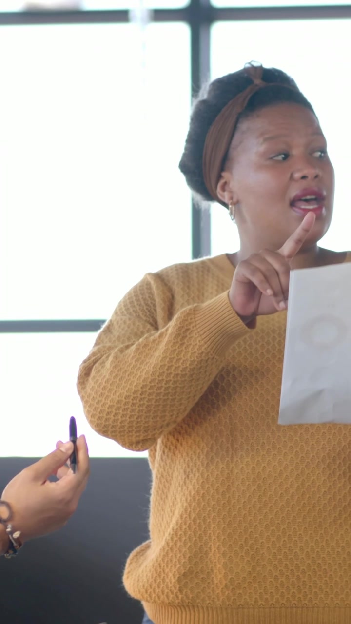 Uomo che offre una penna facendo riferimento a un tablet, donna che accetta un foglio e legge grafici per una revisione aziendale.