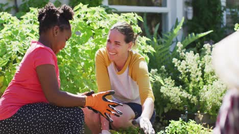 Glückliches-Kaukasisches-Lesbisches-Paar-Und-Ihre-Afroamerikanische-Tochter,-Die-Gemeinsam-Im-Garten-Arbeiten