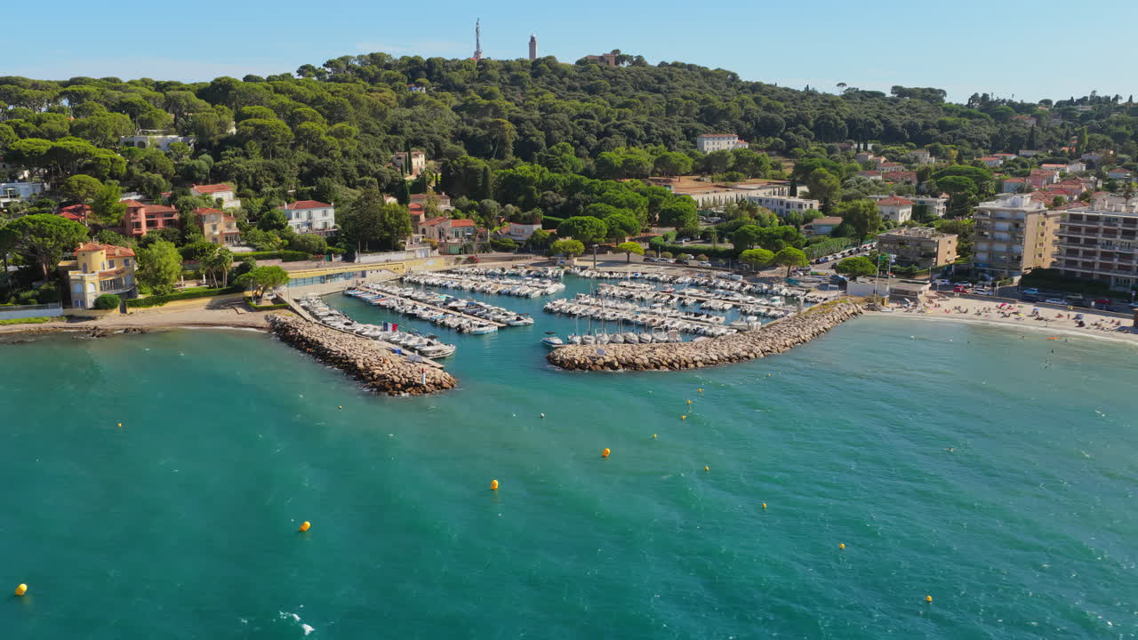 Aerial drone view of Antibes small port and marina with sailboats docked, sandy beaches, and green hills in the background