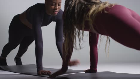 studio shot of two women wearing gym fitness clothing facing each other exercising 7