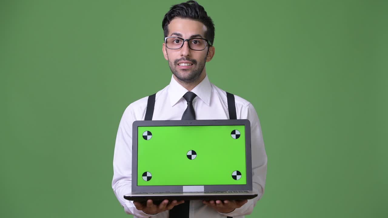 joven empresario persa barbudo y guapo contra un fondo verde