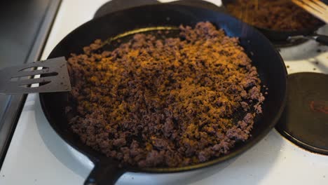 putting taco spice on some ground beef laying in a hot cast iron