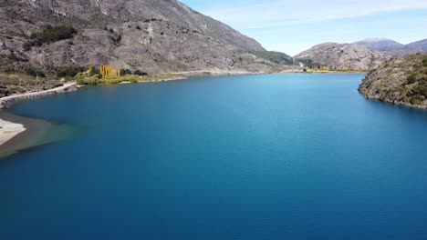 top aerial drone panoramic view beautiful snowy mountains landscape and a turquoise lake along gravel road carretera austral in patagonia, chile