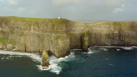 aerial orbit of the cliffs of moher on a sunny, windy, and wavy day