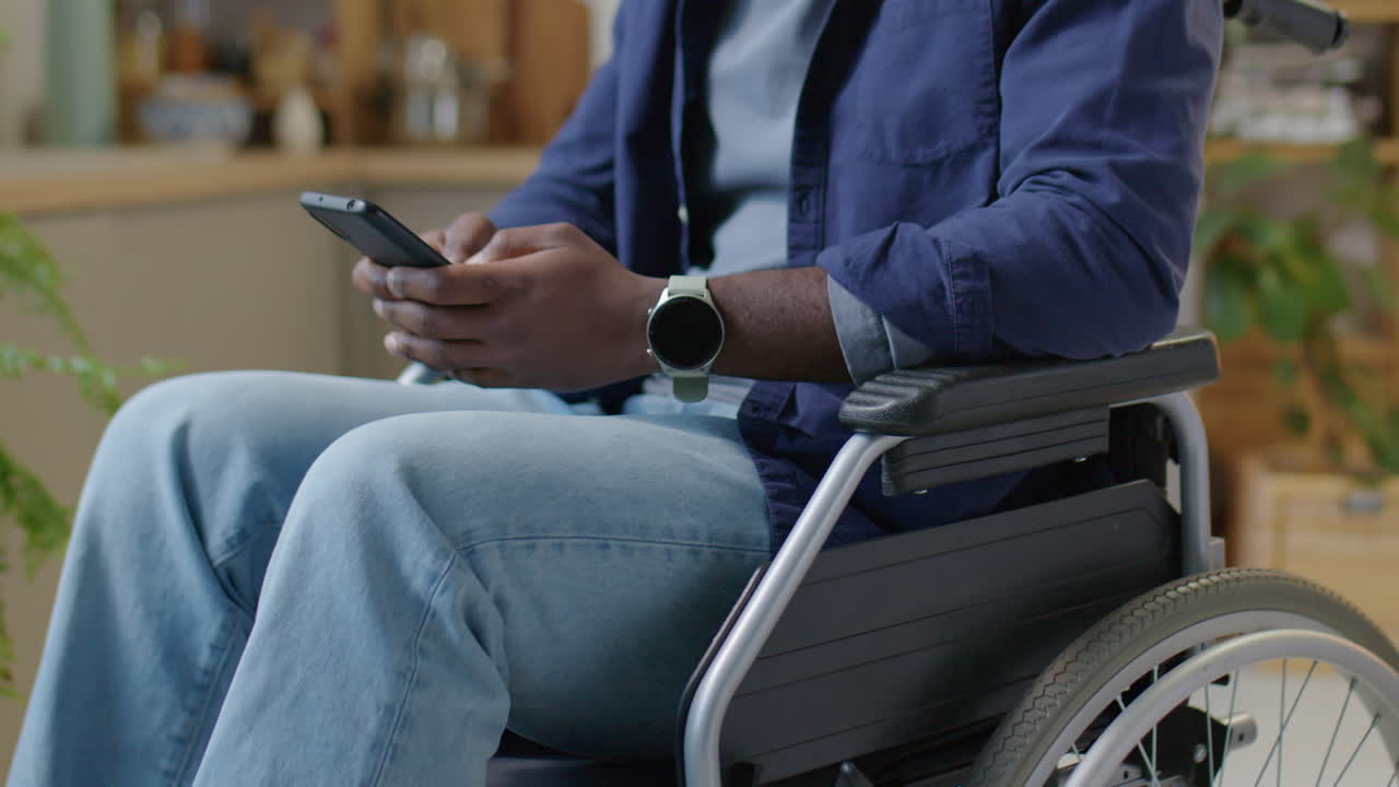 Man in Wheelchair Texting on Phone at Home