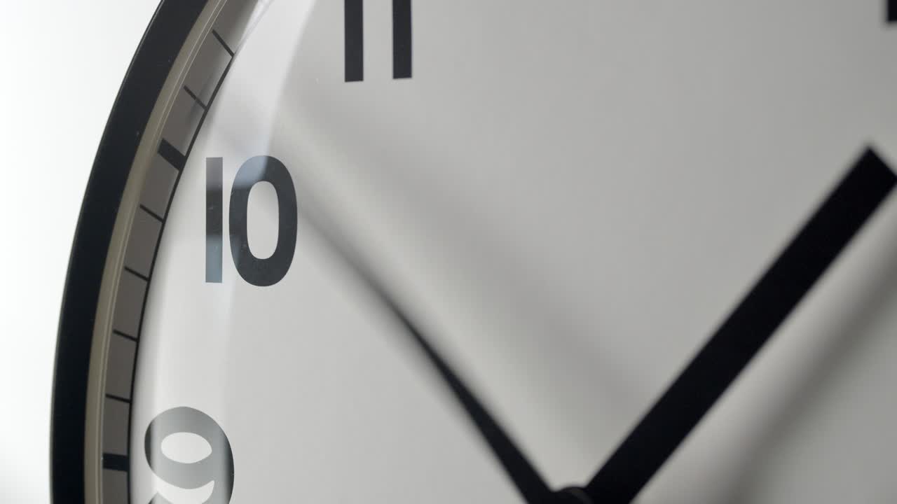 Primo piano del quadrante bianco dell'orologio in time-lapse su parete bianca.