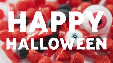 Animation-of-halloween-text-over-sweets-on-grey-background