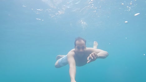 young man deep diving in clear blue water at day from different angle