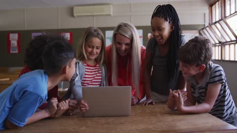 Lehrerin-Und-Gruppe-Von-Kindern,-Die-In-Der-Klasse-Einen-Laptop-Benutzen