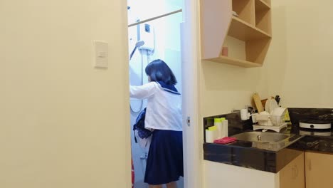 a uniformed schoolgirl enters the apartment's bathroom shower to wash herself