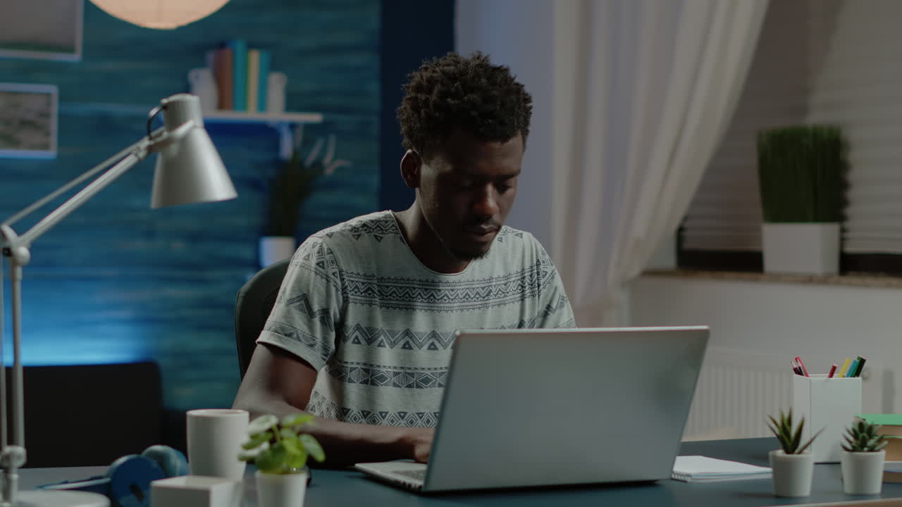 Business man of african ethnicity sitting at desk to work on laptop