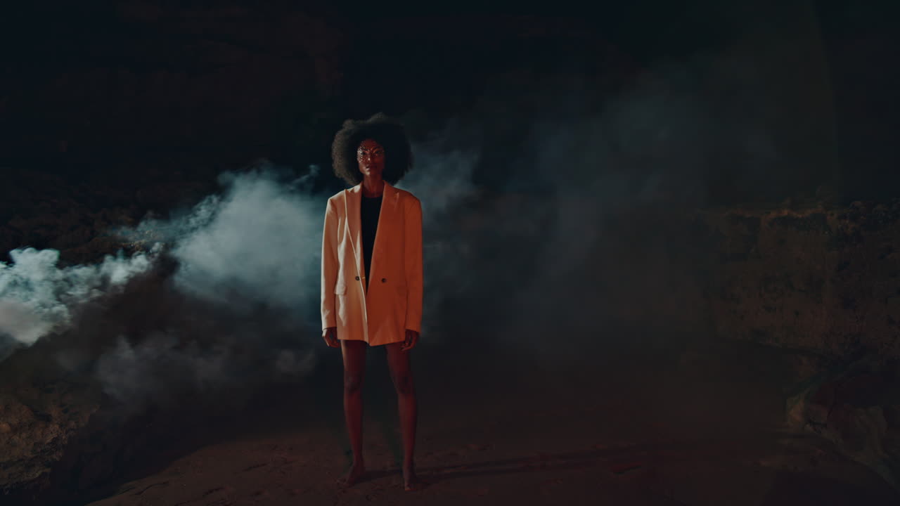 Trendy lady modeling smoke fog on beach. Attractive slim woman looking camera