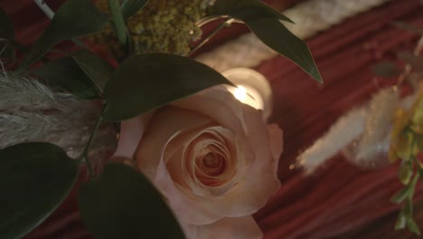 Top-down-shot-of-a-light-pink-rose-and-a-tiny-tea-candle-on-a-wedding-reception-table