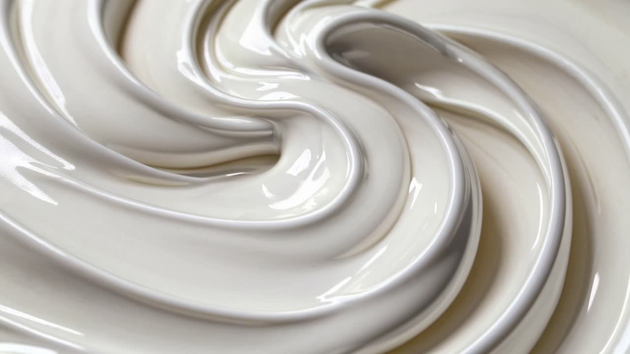 Close-up, top-down view of smooth, creamy texture resembling whipped cream or lotion