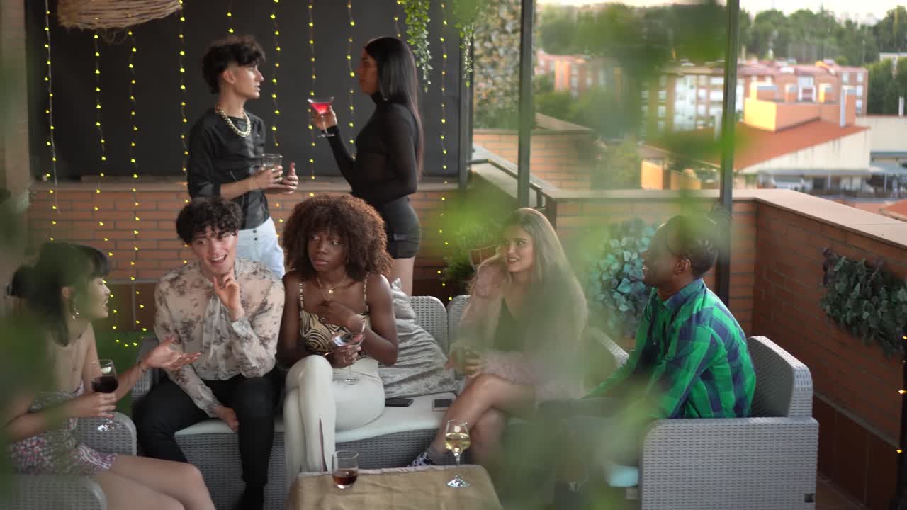 Diverse group of friends socializing and enjoying drinks on a terrace at a party