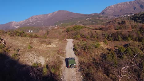 rally rápido coche todoterreno que sale de la sombra de la colina a la pista de tierra