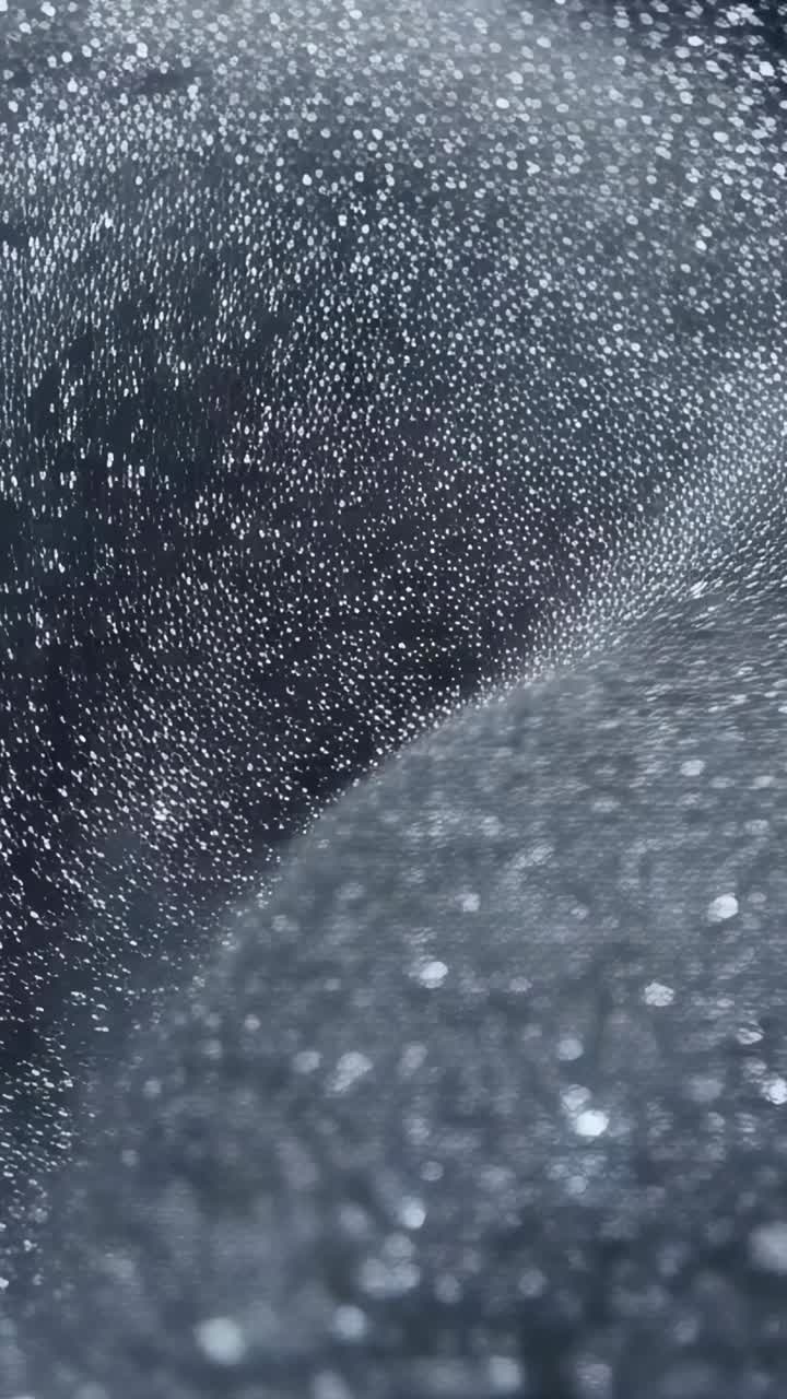 Vertical video: Shifting focus causing fine particles drifting over dark backdrop with bokeh discs