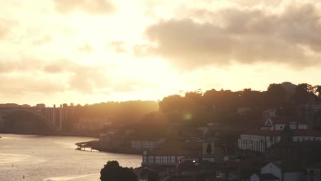 wide shot showing beautiful golden sunset behind cityscape of oporto and douro river in portugal