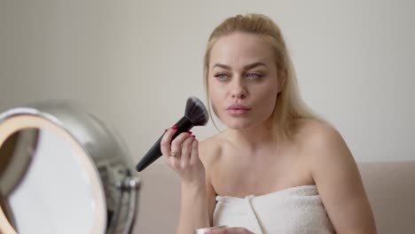 blond woman applying makeup in morning