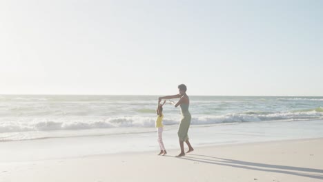 Happy-african-american-mother-and-daughter-dancing-at-beach,-in-slow-motion,-with-copy-space
