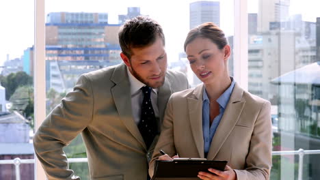 Business-partners-discussing-notes-on-clipboard