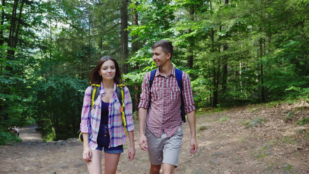 젊은 매력적인 부부는 숲 하이킹과 활동적인 라이프스타일을 걷고 있다