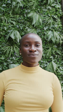vertical video of portrait of happy african american businesswoman over plants in slow motion