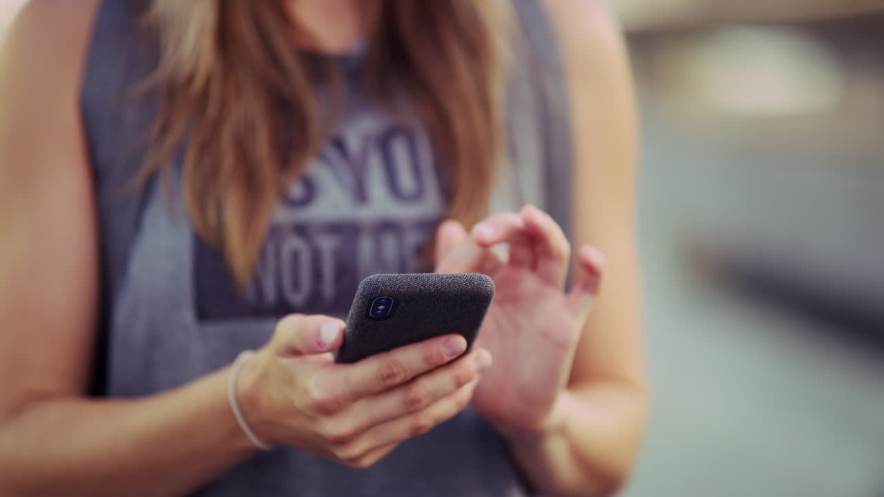 una mujer joven usando su teléfono celular mientras está fuera