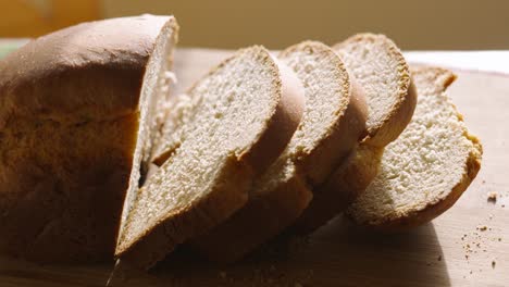 Rotating Clip of Homemade Freshly Baked White Bread with Slices on Wooden Chopping Board with Crumbs in Natural Light. Home Baking Footage with Simple Healthy Ingredients 4K.