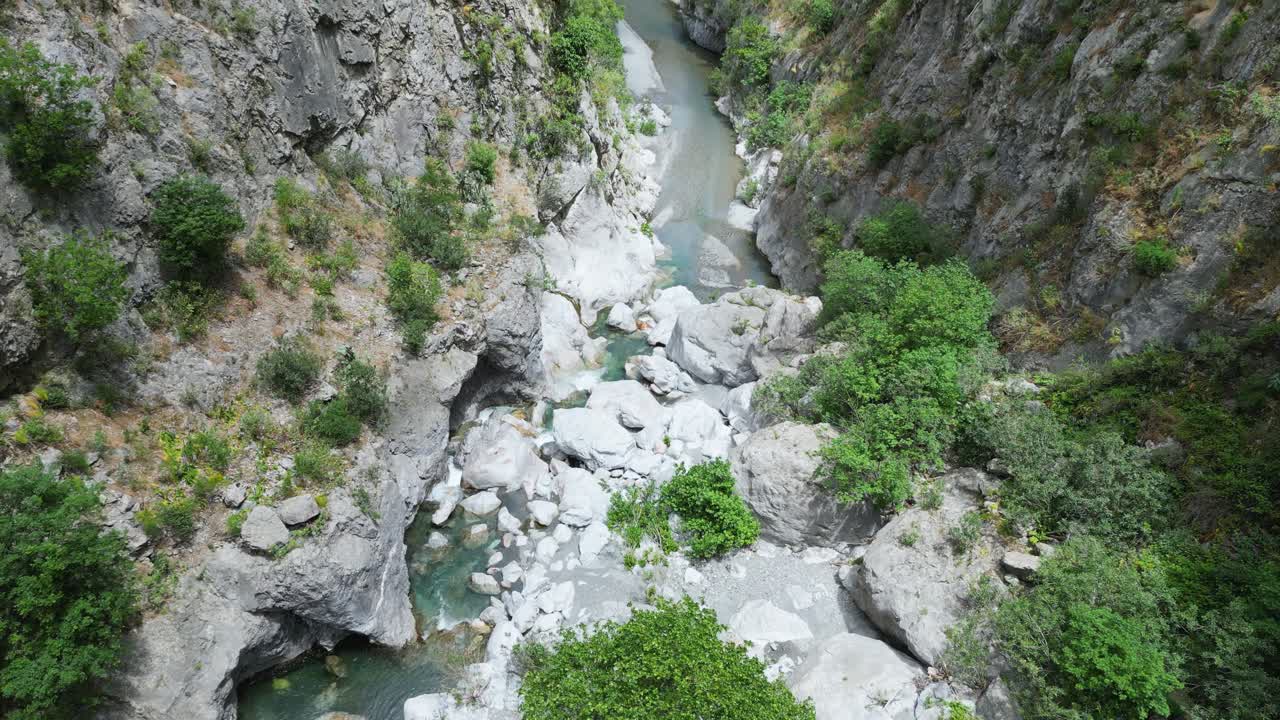 Aerial drone footage of Gole Ranciara, Sicily: rocky canyon with turquoise river, lush vegetation, and dramatic cliffs. Perfect for nature, adventure, and travel documentary projects