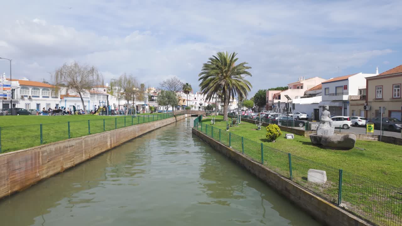 Parco verde e canale con palma e statua a Ferragudo, Portogallo