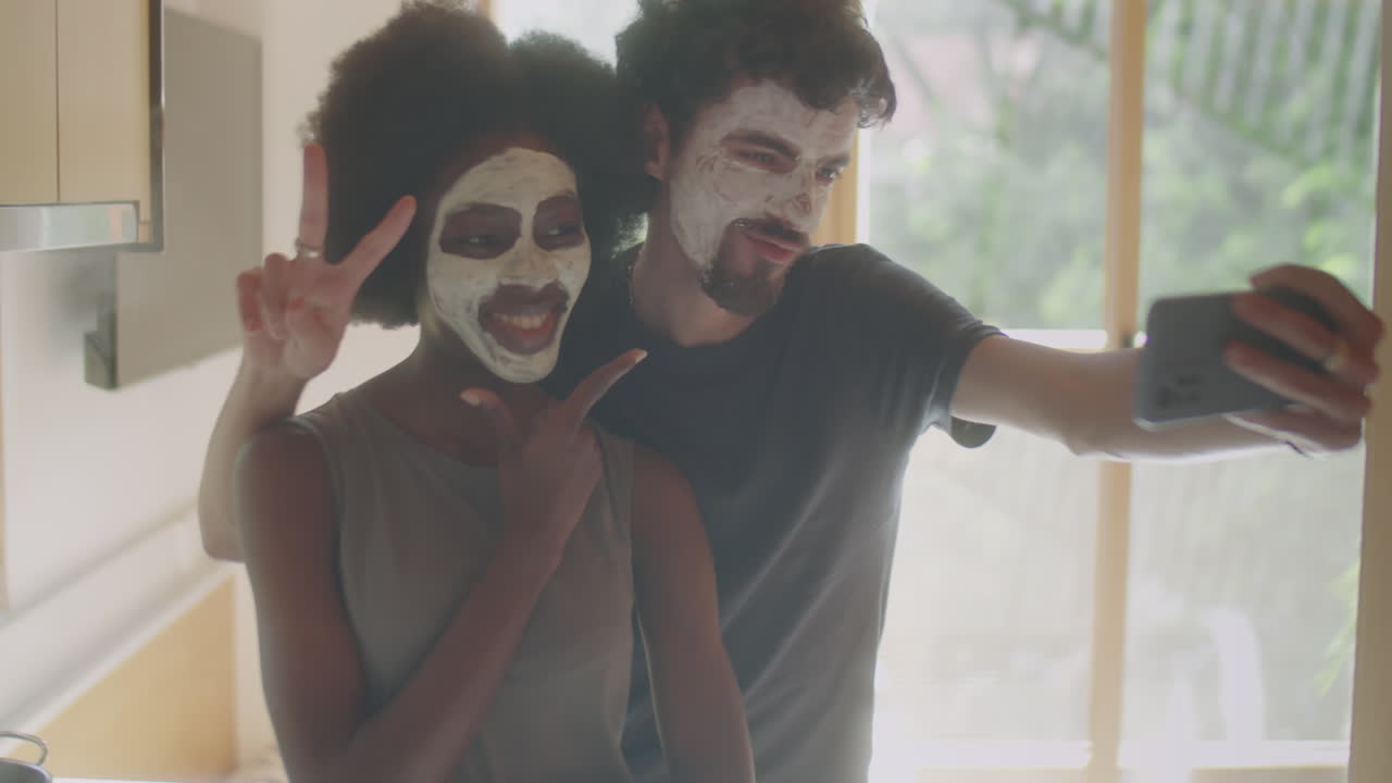 Couple with Cosmetic Face Masks Taking Selfie at Home