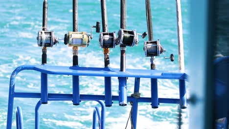 fishing rods lined up on a boat in phuket, thailand, with vibrant blue ocean waves in the background