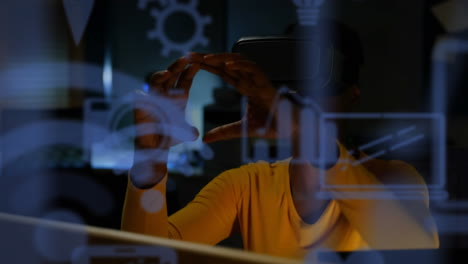 blue digital icons floating against african american businesswoman wearing vr headset at home
