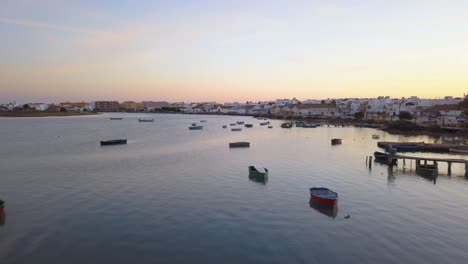 low aerial shot over fishing boats near white houses in barbate, cadiz