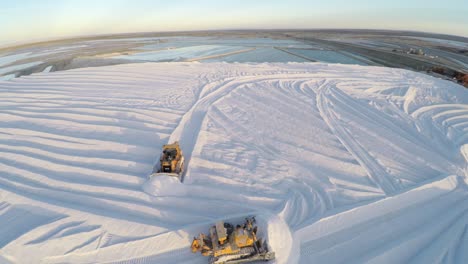 Toma-Aérea-De-Tractores-Trabajando-En-Un-Gran-Depósito-De-Sal-En-Las-Salinas-Por-Evaporación-Solar-En-Guerrero-Negro,-Laguna-Ojo-De-Liebre,-Reserva-De-La-Biosfera-De-El-Vizcaino,-Baja-California-Sur