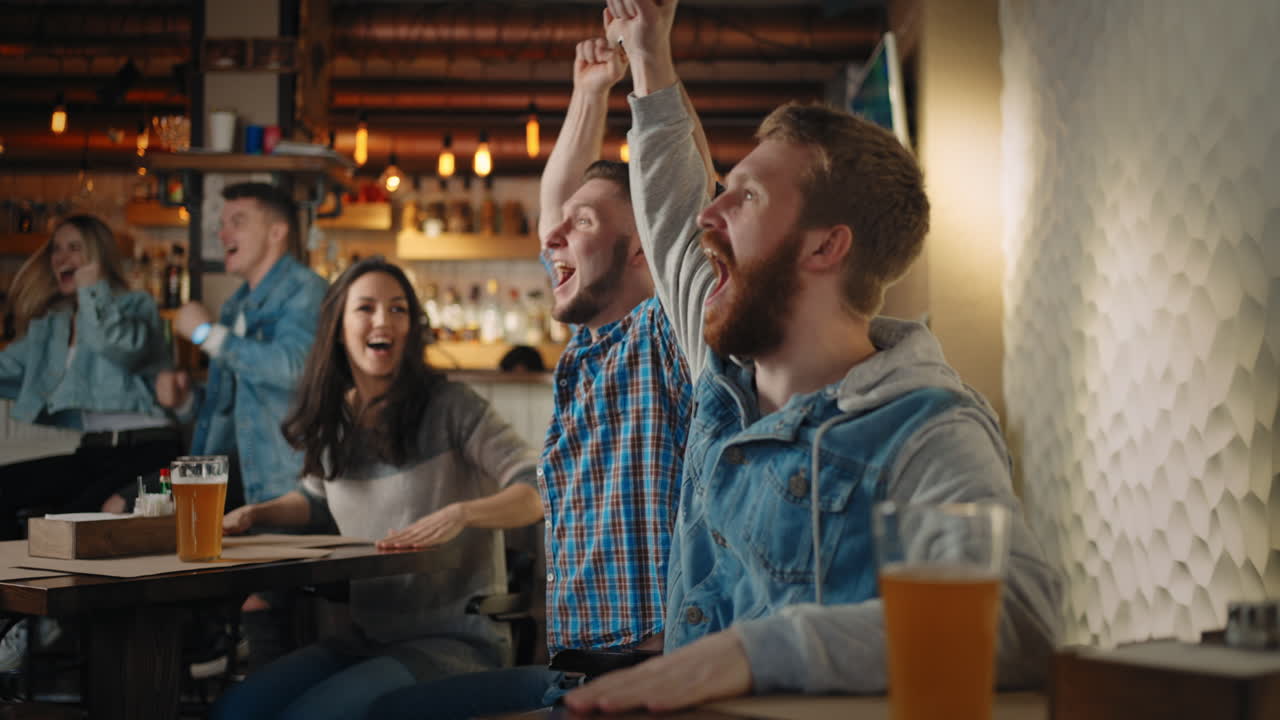 A group of men and women in a pub together cheer for their national team at the World Cup in football basketball hockey. Celebrate the goal scored the puck