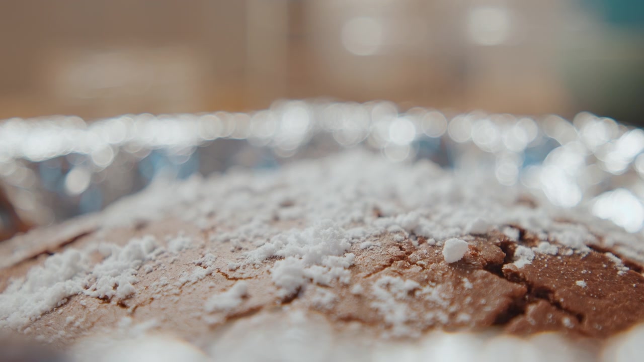 Moist chocolate treat with gentle lighting. Crackedtopped chocolate cake dusted with soft powdered sugar. Cozy kitchen scene featuring moist chocolate cake with sugary dusting and natural light