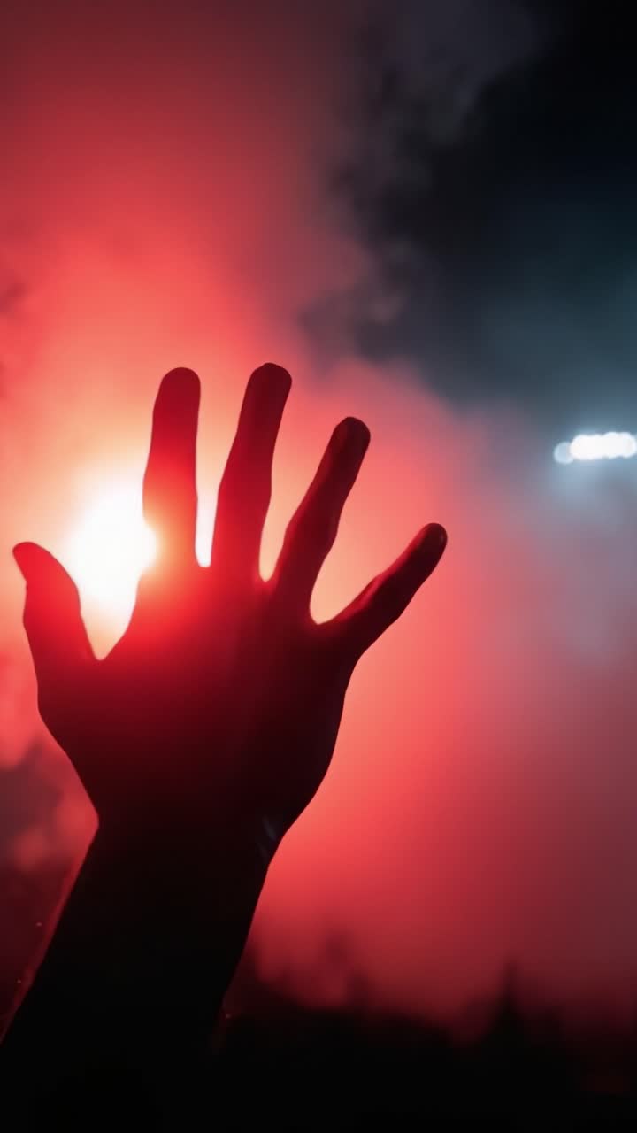 A striking visual of a hand reaching out amidst a vibrant display of red smoke and light, capturing the essence of passion and emotion in a dramatic atmosphere
