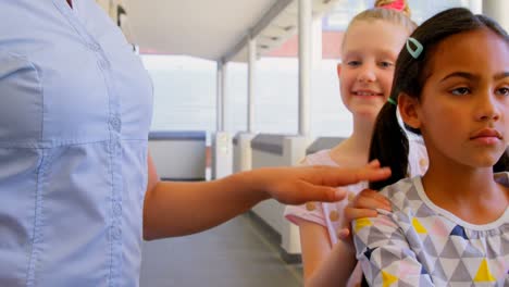 Schoolkids-with-teacher-standing-in-row-with-their-hands-on-shoulder-in-corridor-at-school-4k