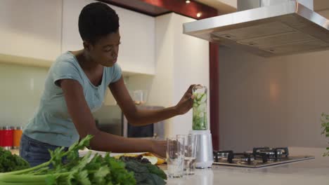 african american attractive woman blending ingredients for smoothie in kitchen