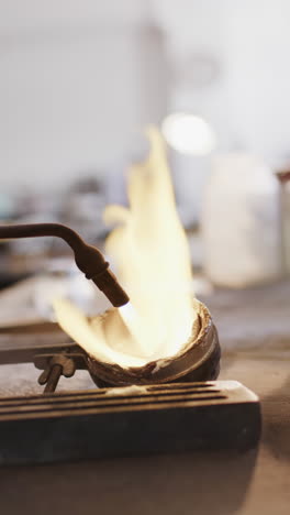 vertical video of close up of melting metal with blowtorch in workshop in slow motion