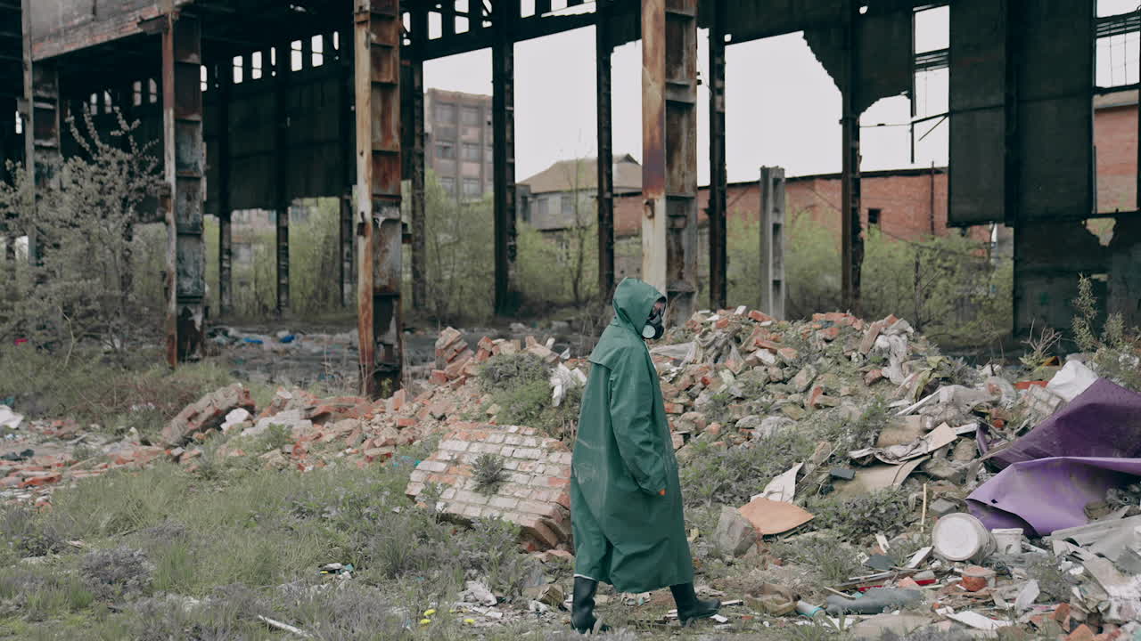 Person in chemical protective suit walking in distracted place. Survivor in abandoned place with piles of garbage from ruined buildings. Apocalypse concept.