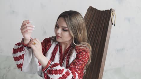 Una-Mujer-Con-Una-Auténtica-Camisa-Y-Falda-Ucranianas-Bordadas-Posa-Y-Ajusta-Su-Cabello-Mientras-Mira-A-La-Cámara