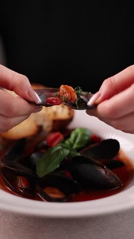 woman enjoying a delicious seafood soup with mussels