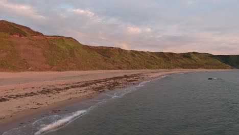 Vista-Aérea-De-La-Costa-Sobre-El-Mar-A-Lo-Largo-De-La-Playa-De-Arena-Con-Vistas-Al-Borde-Del-Acantilado-En-Porth-Neigwl-En-La-Península-De-Llyn-En-El-Norte-De-Gales