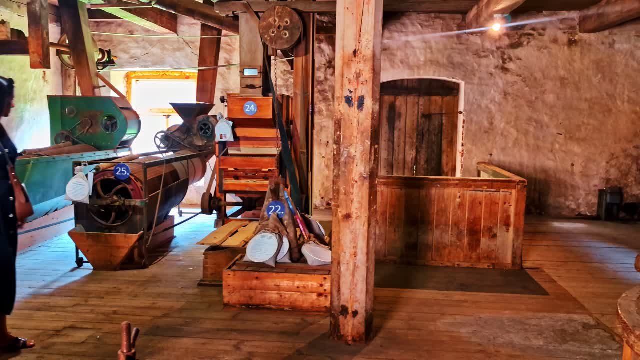 Pan across woman exploring historic woodshop with workbenches and vintage equipment